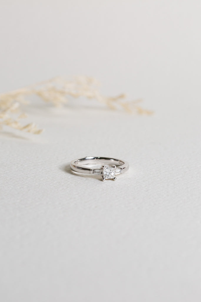 White gold diamond engagement ring with a princess cut diamond in the centre, and tapered baguette diamonds on the sides