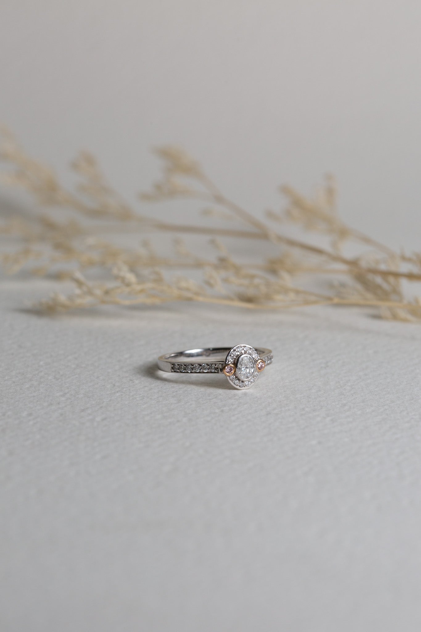 White gold oval-cut diamond engagement ring with natural pink diamonds