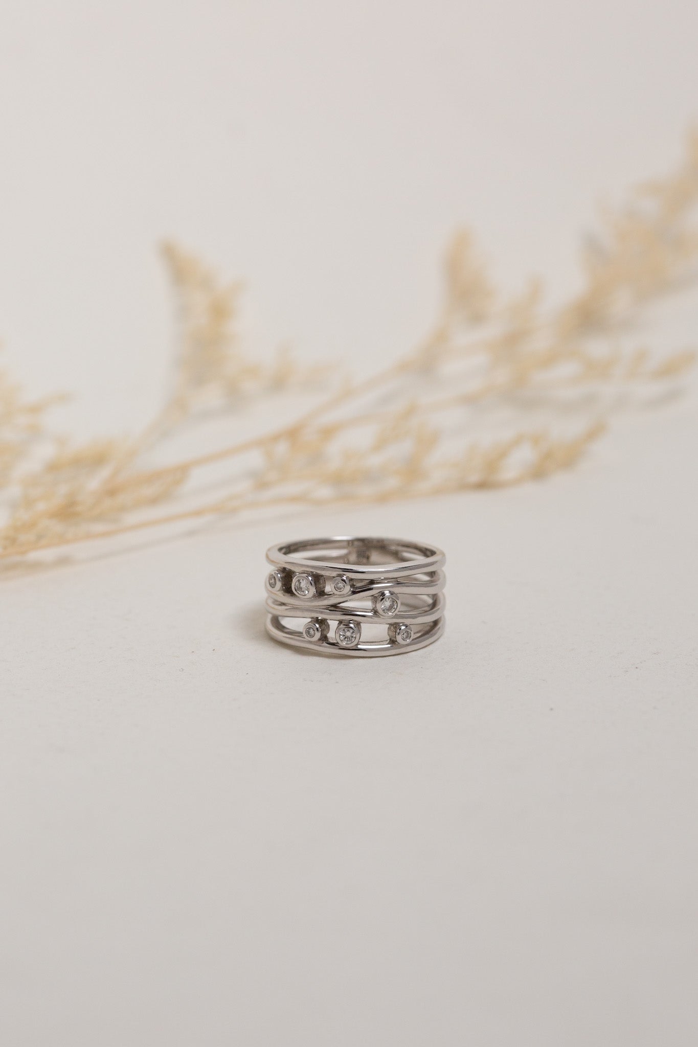 9ct white gold diamond dress ring.  The ring is wide with 7 diamonds bezel-set on it.