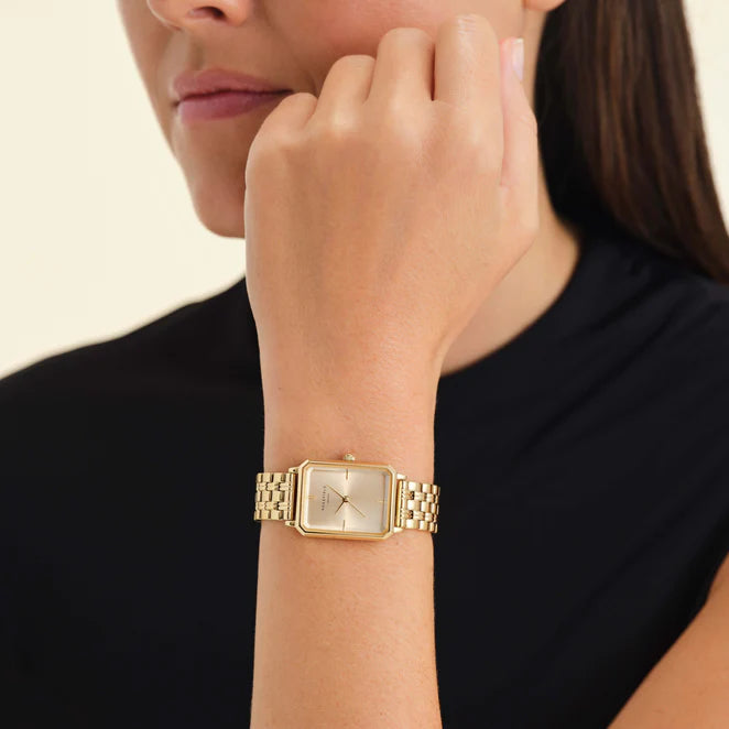 A model is wearing a gold octagon watch