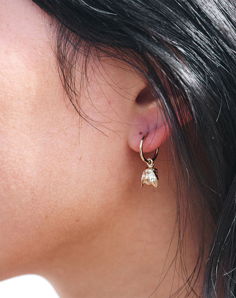 Silver bee hoop earrings shown on the ear