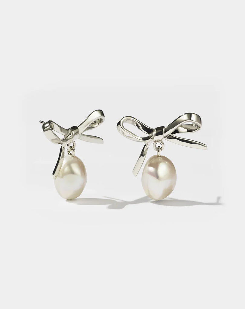 Silver bow earrings with pearls hanging from them