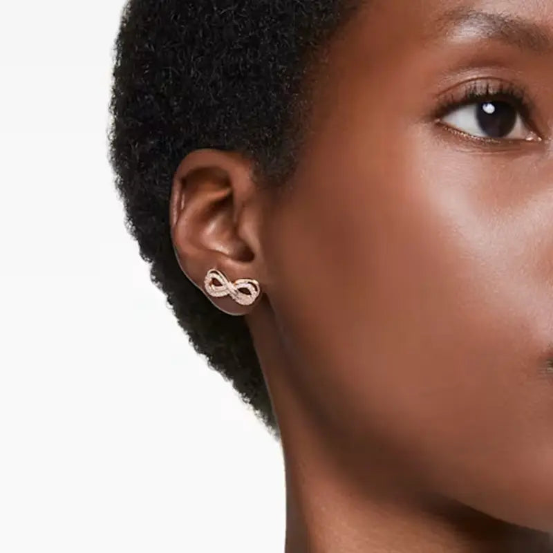 Rose gold infinity symbol stud earrings, worn by a model