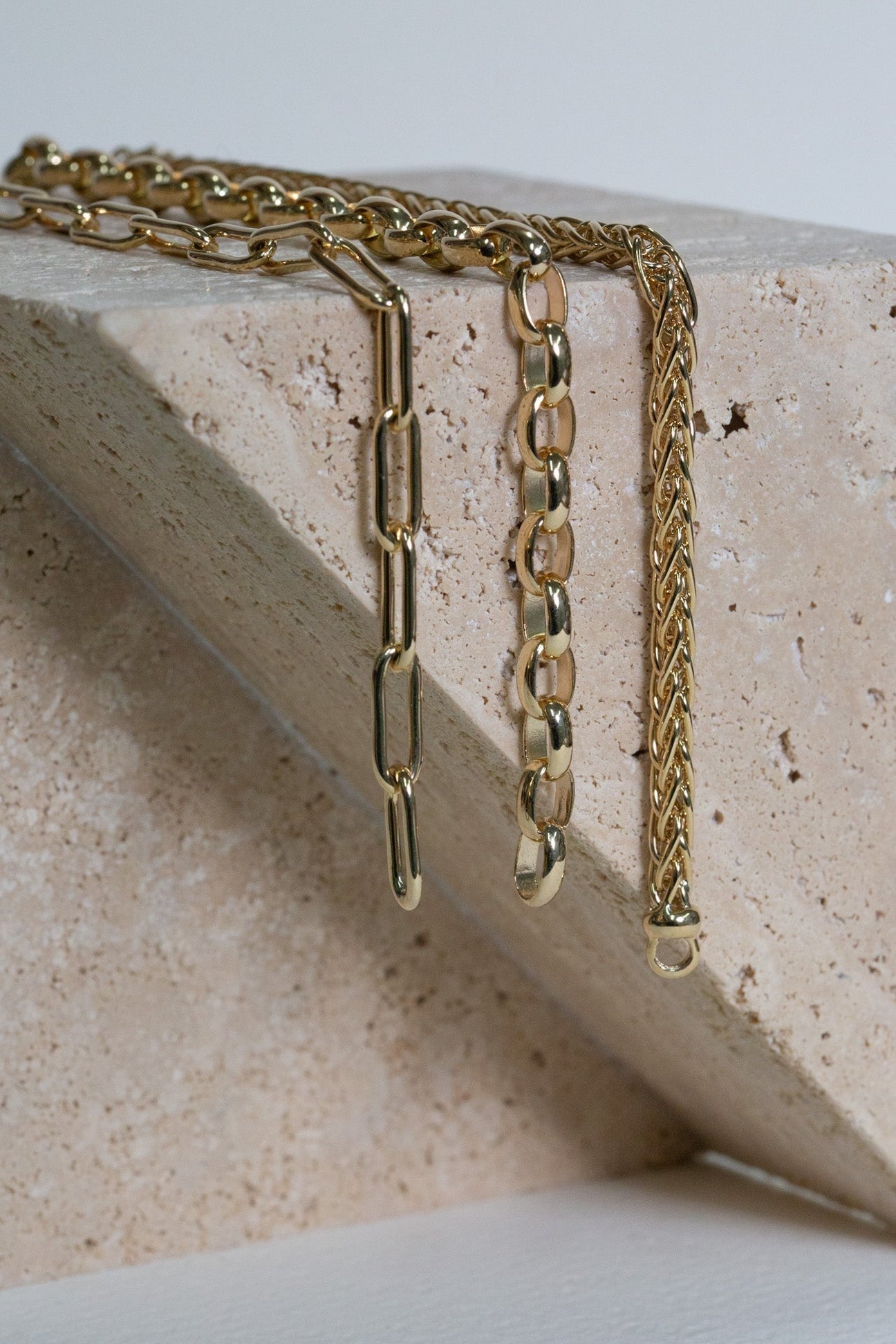 Gold paperclip chain, oval belcher chain, and wheat chain bracelets.