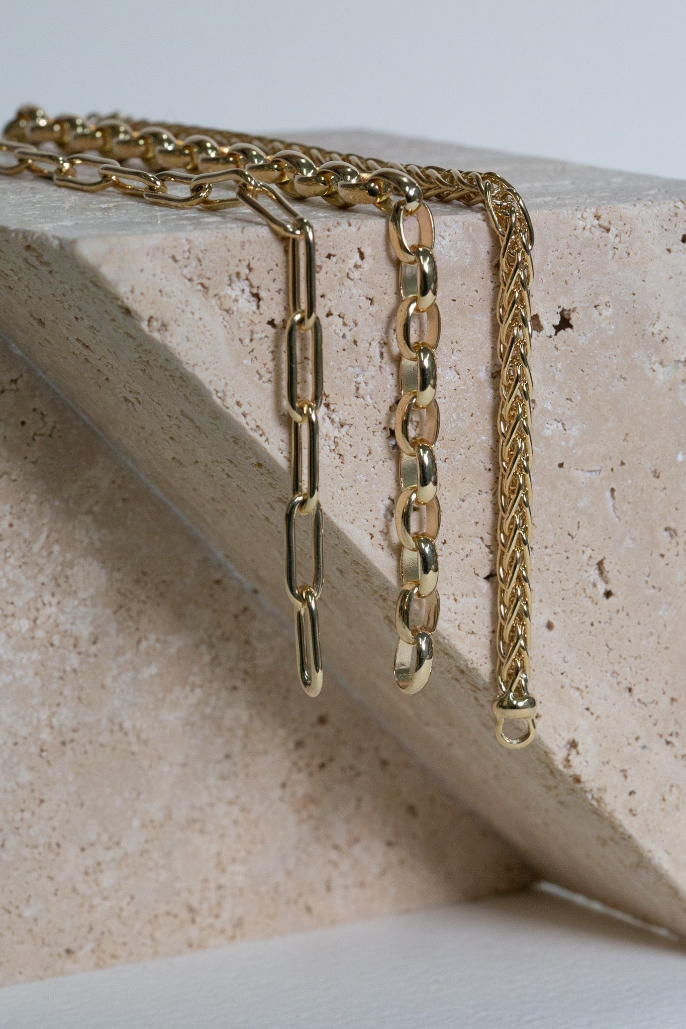 Gold paperclip chain, oval belcher chain, and wheat chain bracelets.