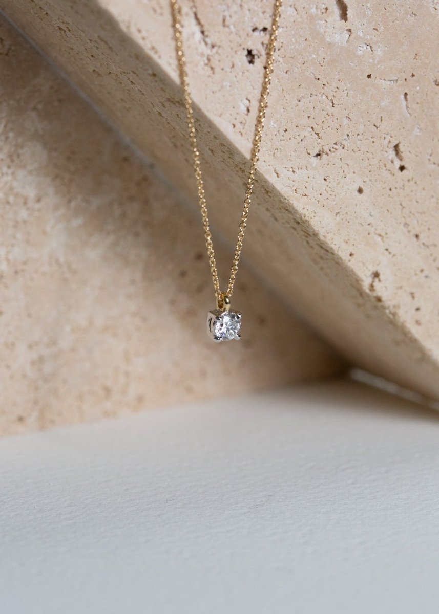 A 9ct yellow gold 0.50ct diamond solitaire pendant is hung from a 9ct gold chain.
