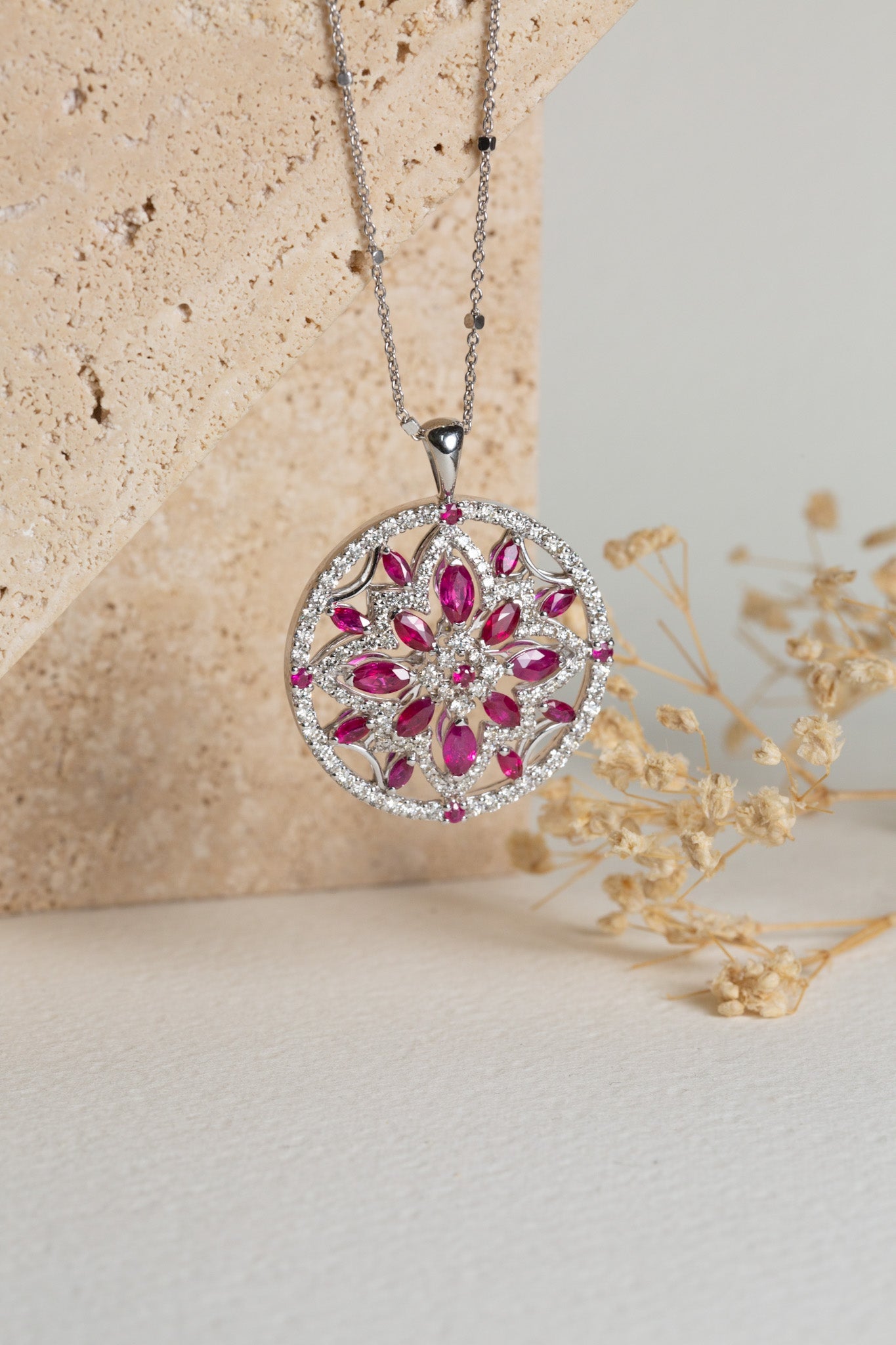A white gold pendant featuring natural rubys and diamonds