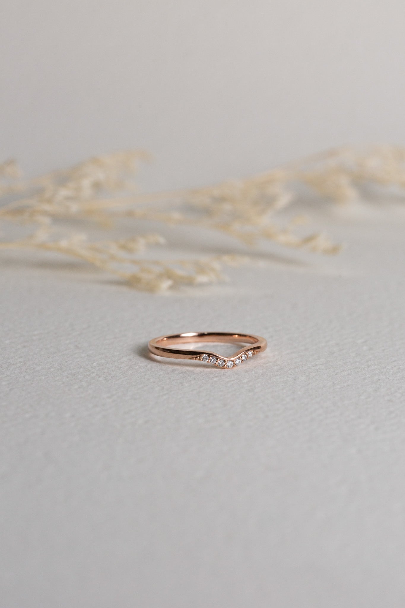 Rose gold diamond band which is shaped to sit around an engagement ring