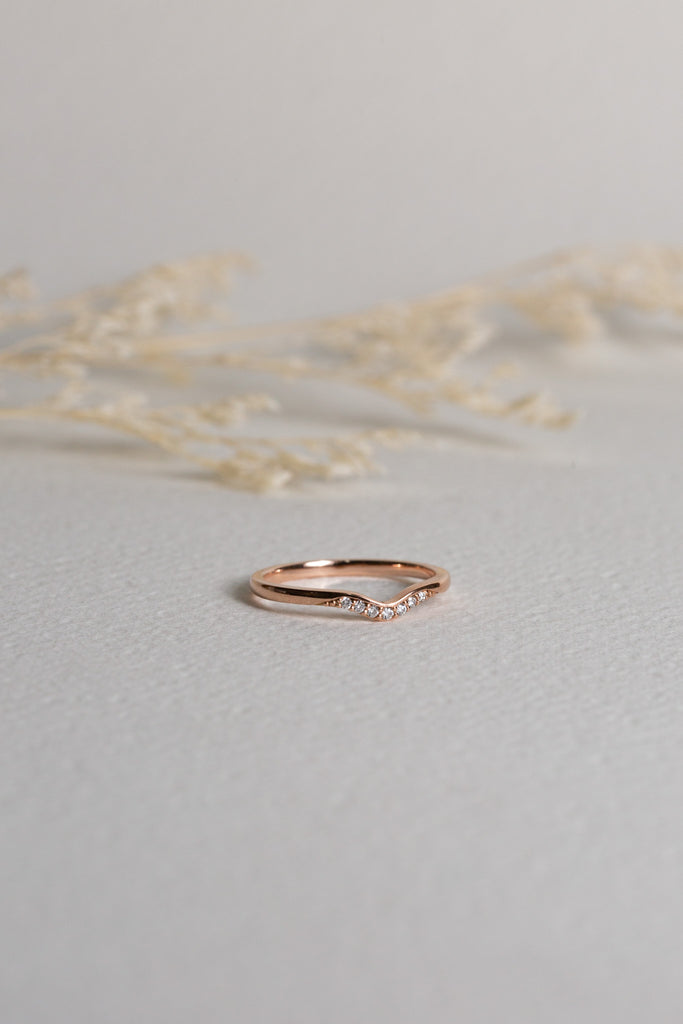 Rose gold diamond band which is shaped to sit around an engagement ring
