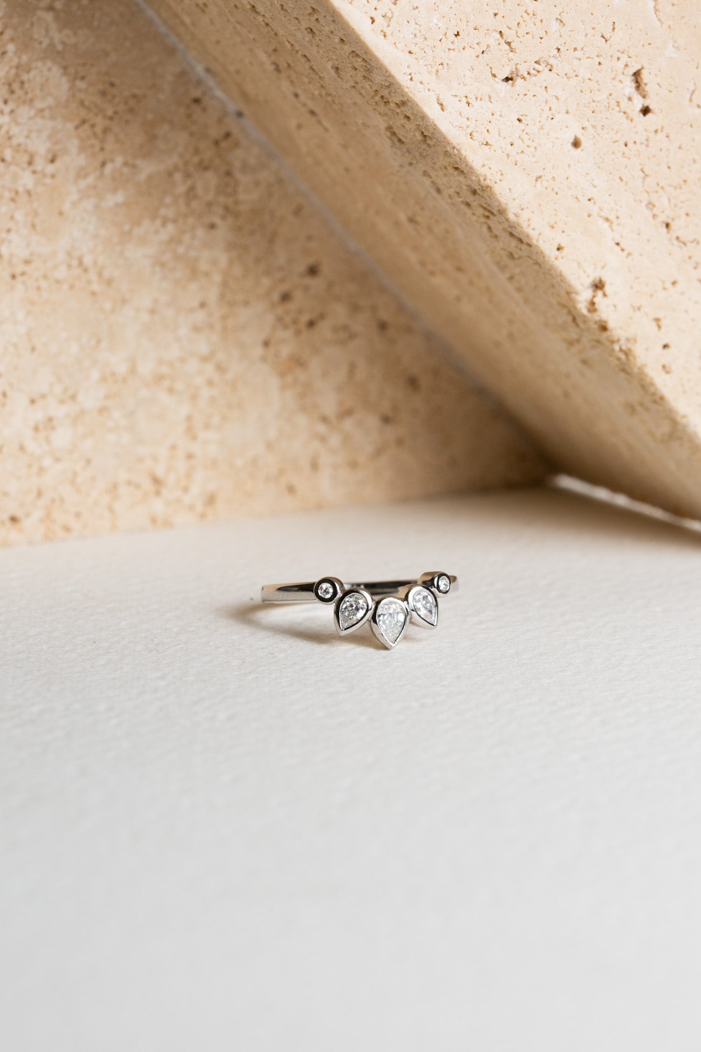 Platinum wedding ring with pear-cut diamonds.  The ring is curved to shape around an engagement ring