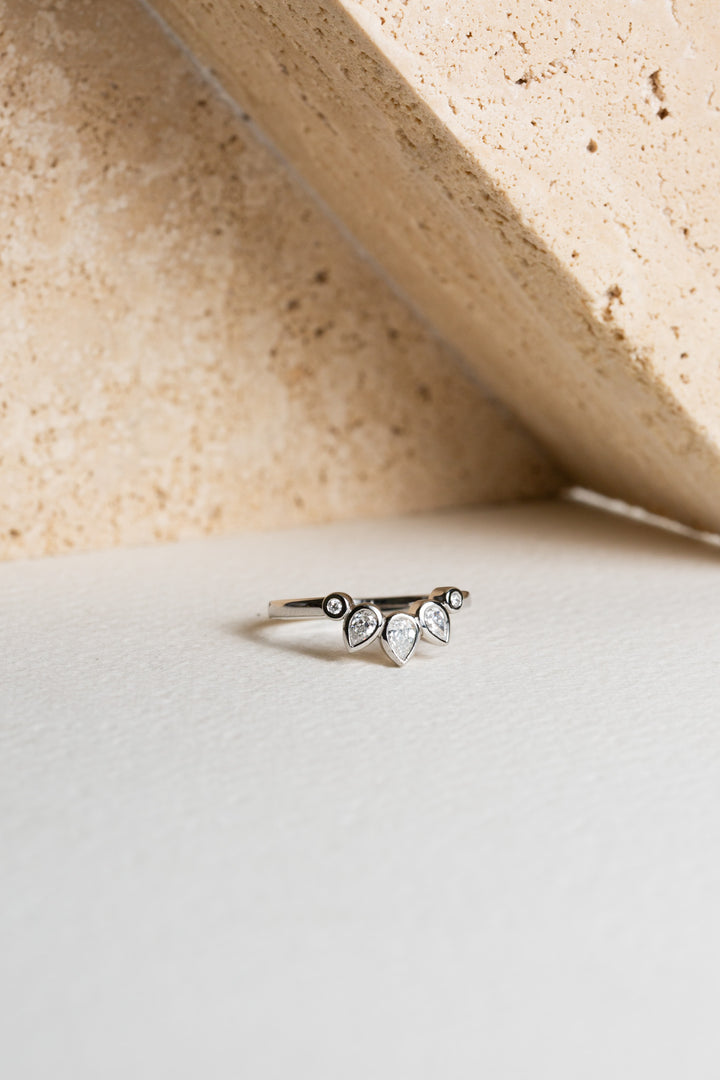 Platinum wedding ring with pear-cut diamonds.  The ring is curved to shape around an engagement ring