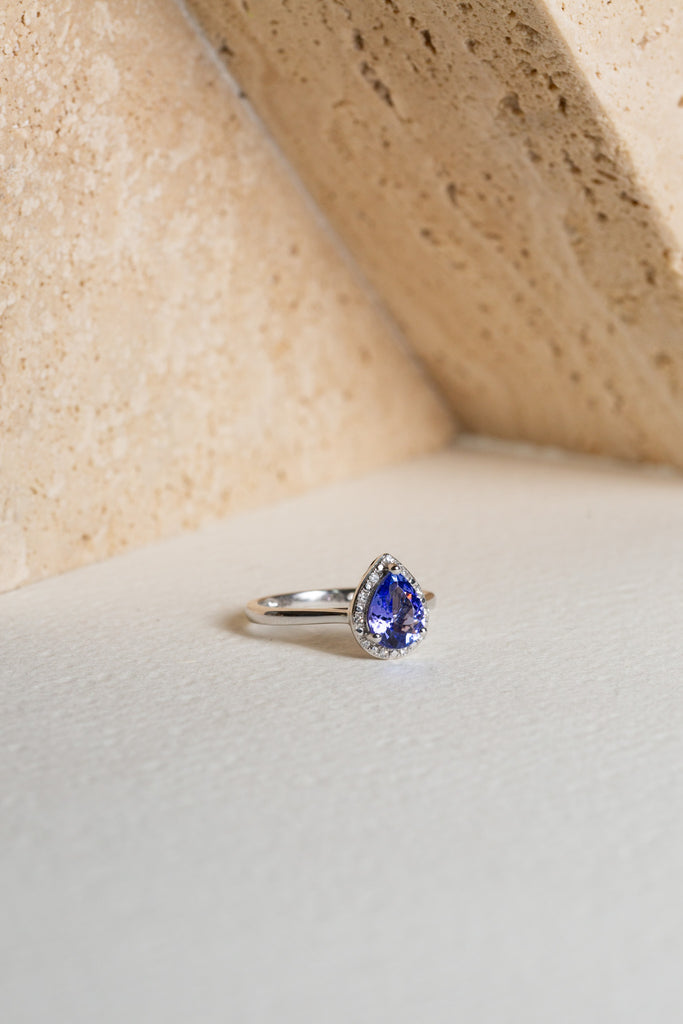 A pear-cut Tanzanite is surrounded by a halo of diamonds.  The ring is crafted from white gold.