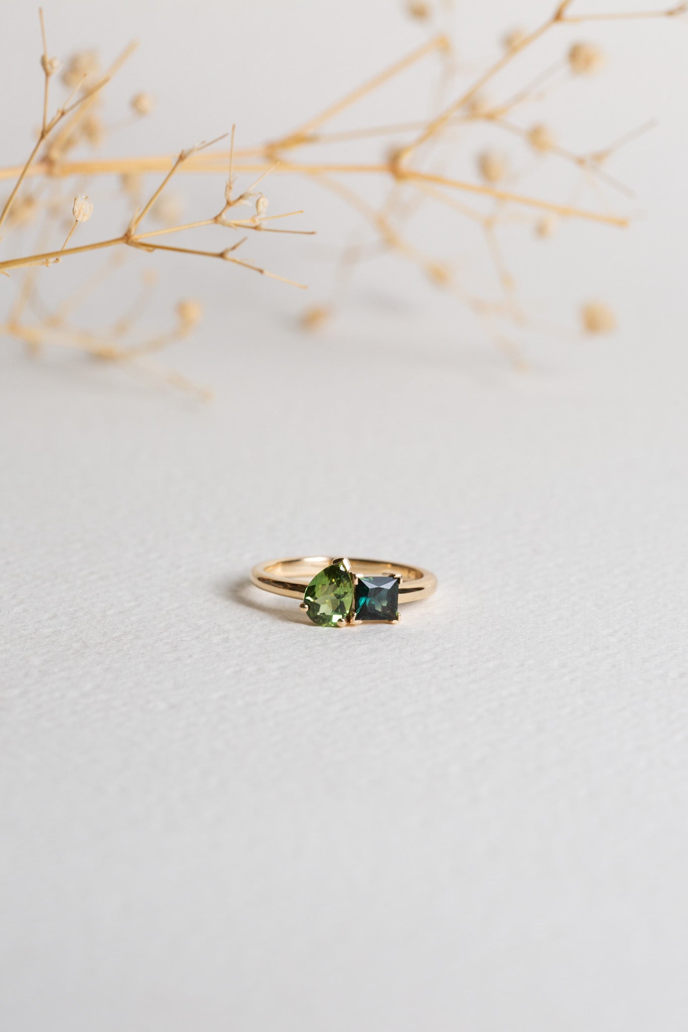 Gold ring with two Sapphires.  One Sapphire is green and pear-cut, the other is teal and princess-cut