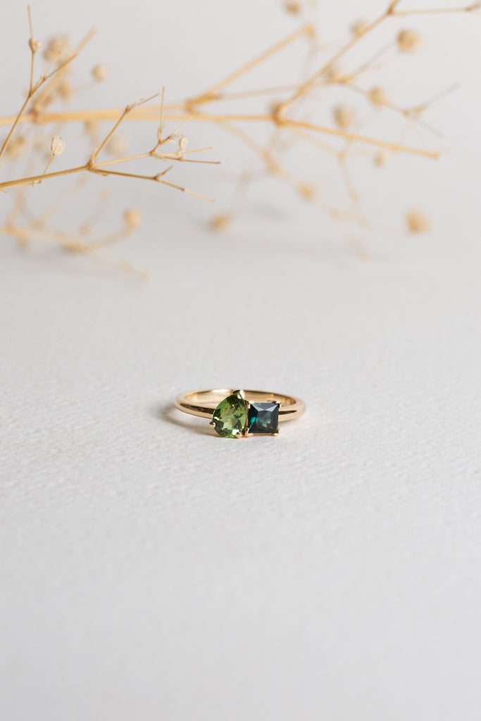 Gold ring with two Sapphires.  One Sapphire is green and pear-cut, the other is teal and princess-cut