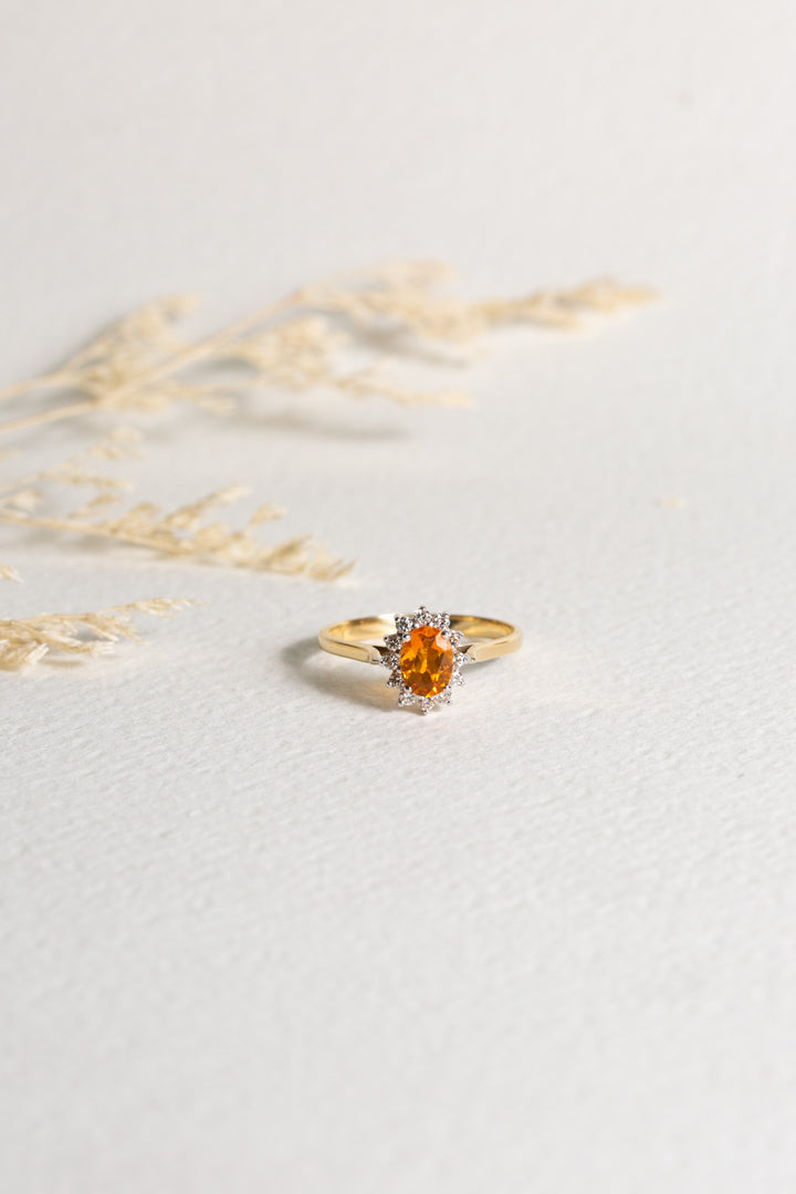 18ct gold ring set with a Fire Opal, which is surrounded by diamonds.