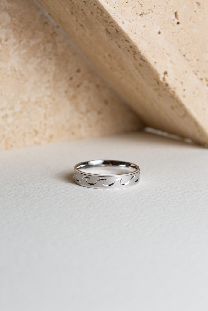 Mens white gold ring with a wave pattern engraved in it