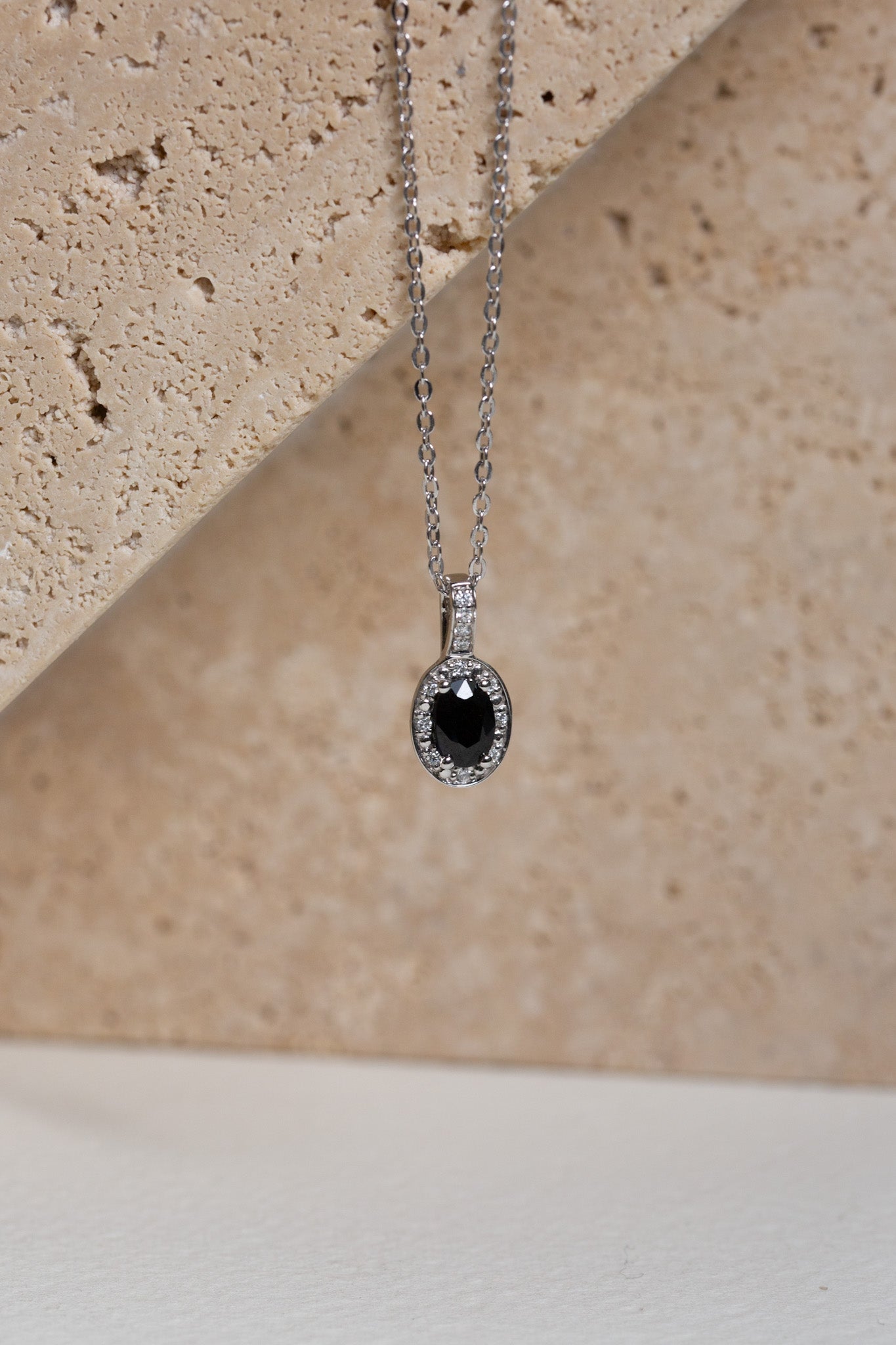 White gold necklace with a sapphire and diamond halo pendant
