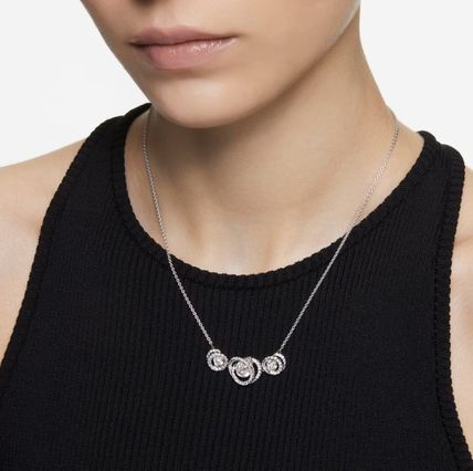 A model in a black tank top is wearing a silver Swarovski necklace
