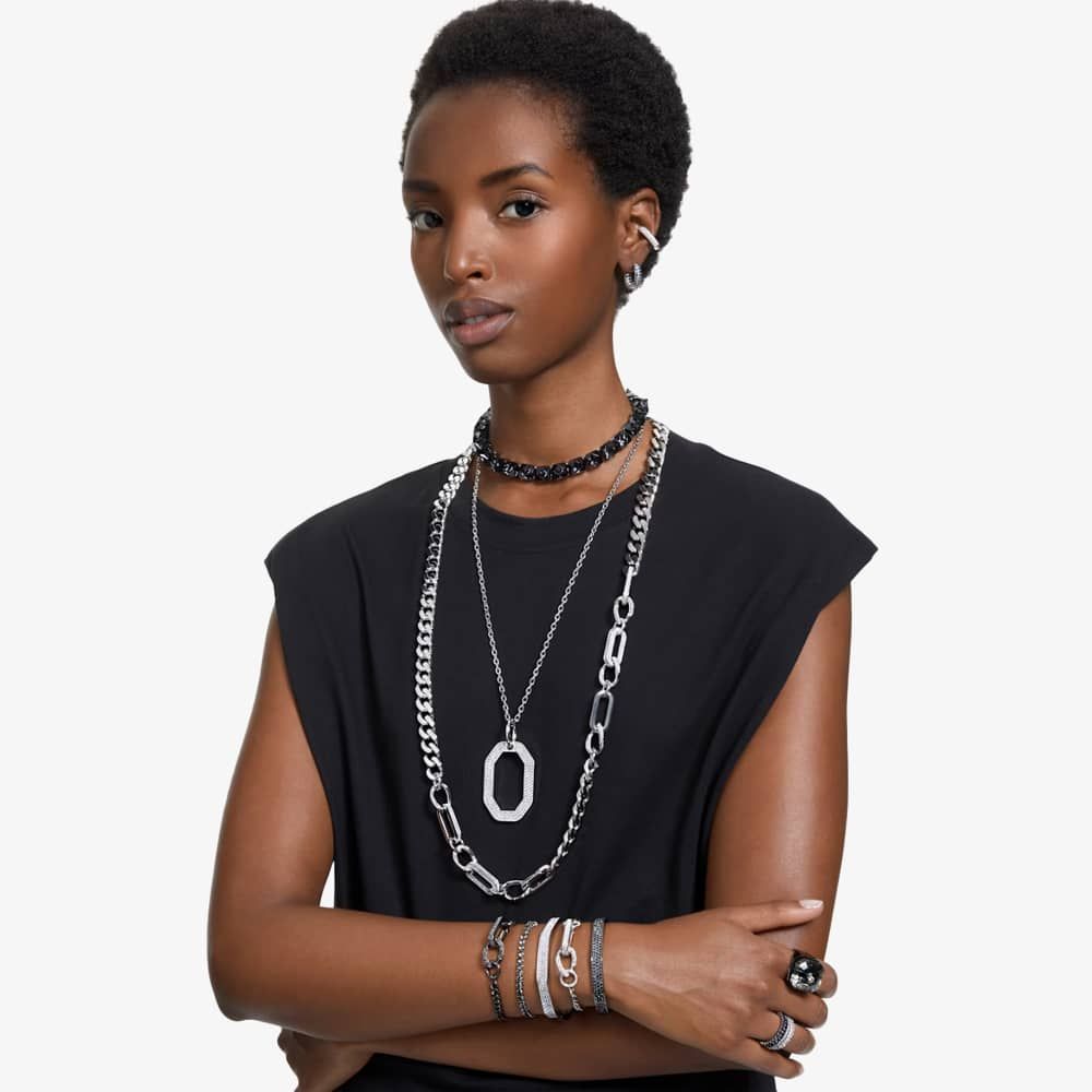 Long layered silver chains are worn by a model 