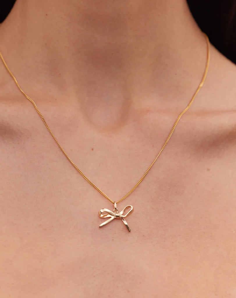 Gold bow necklace worn by a model
