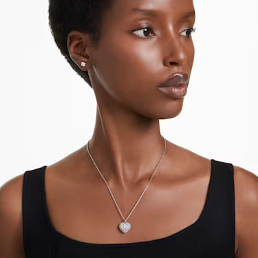 A model is wearing a Swarovski heart necklace, matched with solitaire stud earrings