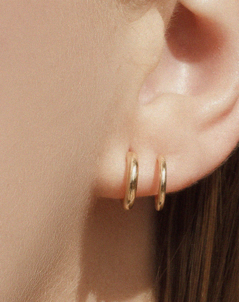 Gold double hoop earrings on an ear