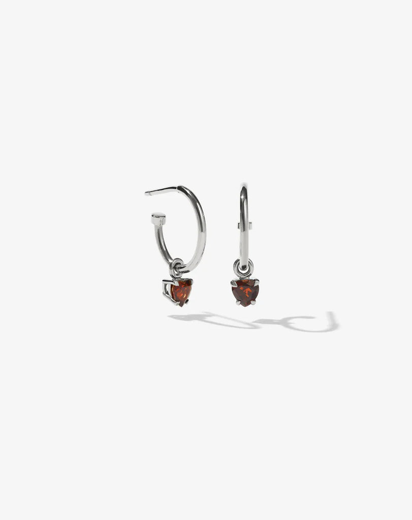 Silver hoop earrings with heart shaped garnets on them