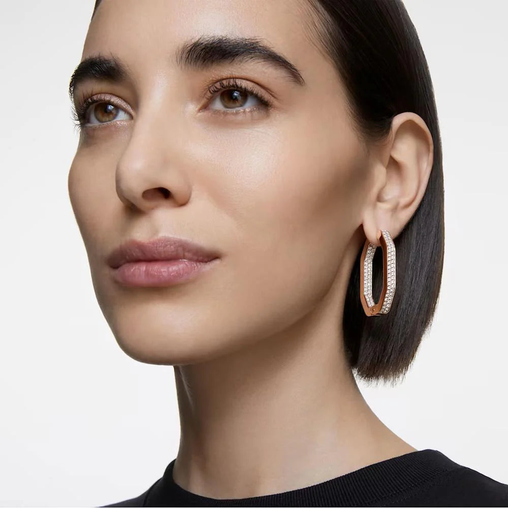 A model is wearing large rose gold hoop earrings, which are set with Swarovski crystals