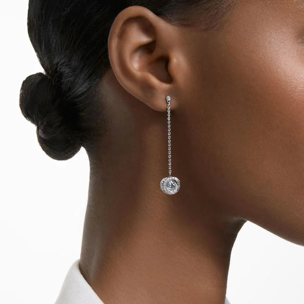A model is wearing a long drop earring which has a Swarovski crystal on the end of it