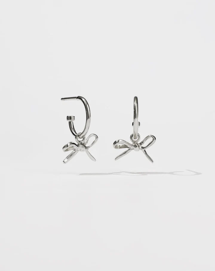 Silver hoop earrings with bows hanging from them