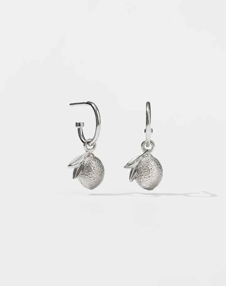 Silver hoop earrings with lemon motifs hanging from them.