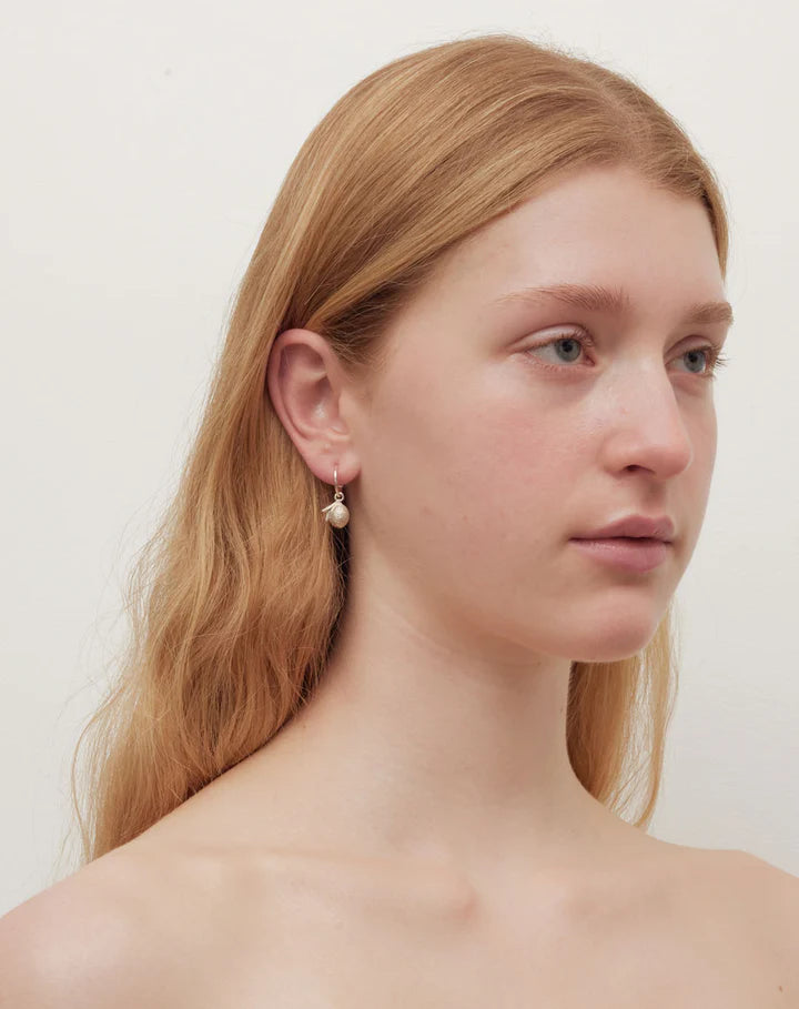 A model is wearing silver hoops