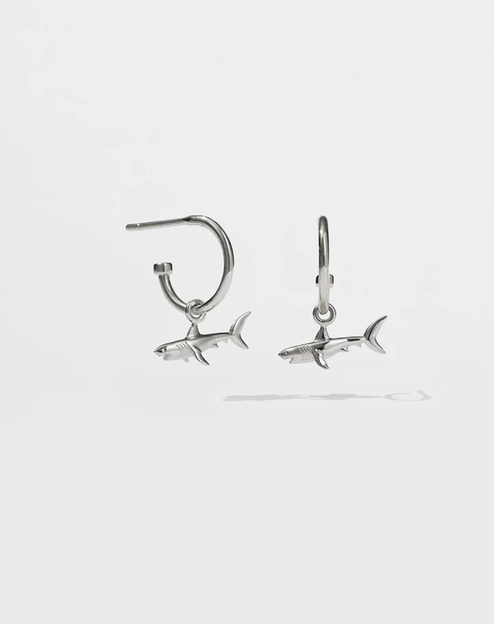 Silver hoop earrings with sharks dangling from them.