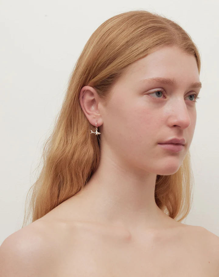 Silver shark hoop earrings, worn by a redheaded model.